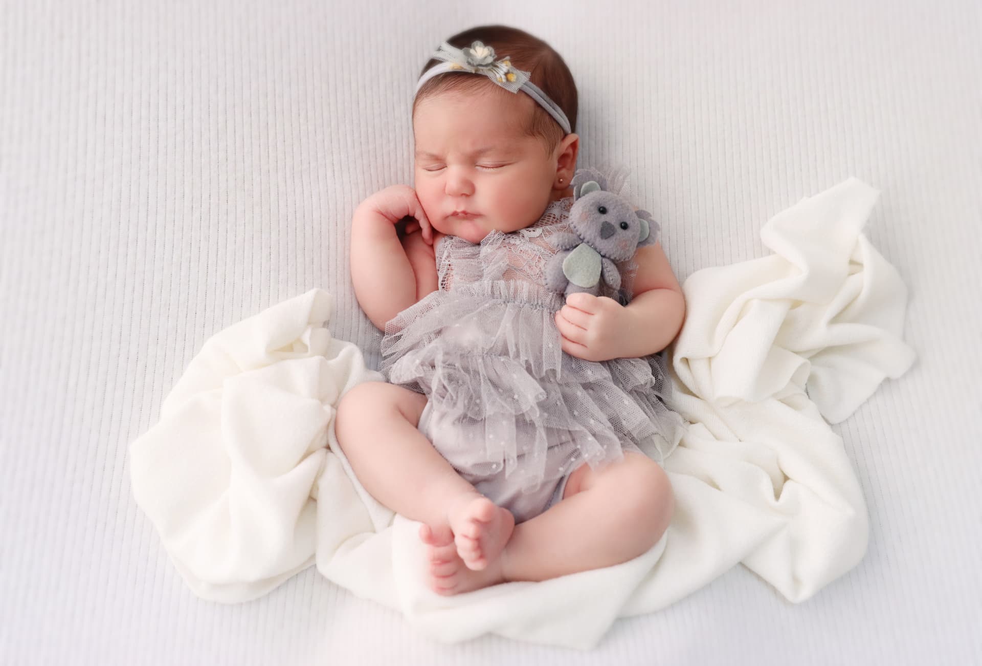 Bebê dormindo com um coala de pelúcia em ensaio newborn do Studio Camila Ruiz
